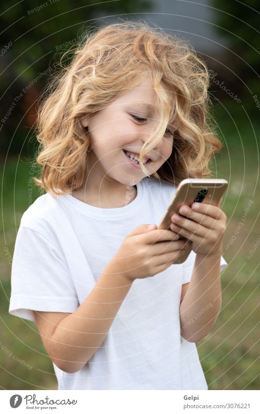Lustiges Kind mit langen Haaren, das ein Handy hält. Lifestyle Freude Glück Freizeit & Hobby Telefon PDA Bildschirm Junge Mann Erwachsene Kindheit Park blond