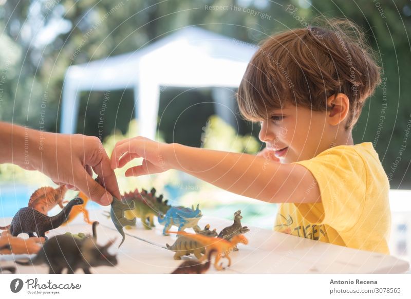 Spielzeug-Dinosaurier auf dem Tisch, Spielen Sommer Garten Kind Schule Junge Mann Erwachsene Eltern Mutter Kindheit Hand Bikini Kunststoff genießen Lächeln