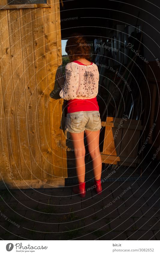 Junge Frau schaut in einen dunklen Stall. Mensch feminin Mädchen Jugendliche Kindheit Haus Hütte Gebäude Tür Blick stehen träumen dunkel schwarz Gefühle