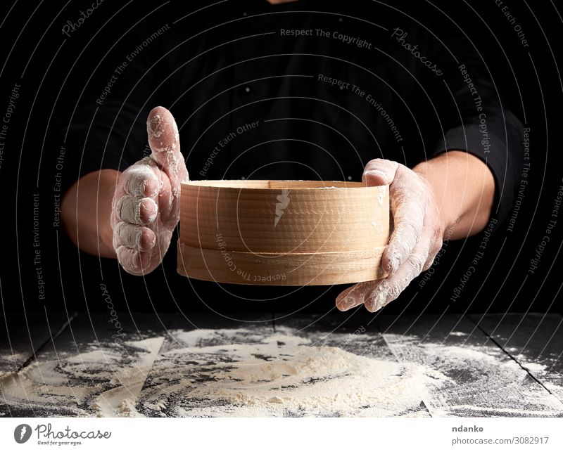 Mann siebt weißes Weizenmehl durch ein Holzsieb. Teigwaren Backwaren Brot Ernährung Tisch Küche Mensch Erwachsene Hand Sieb Bewegung machen frisch schwarz