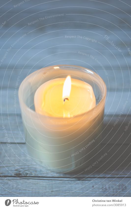 Brennende Kerze in einem Kerzenglas auf hellem Holzuntergrund. Schwache Tiefenschärfe Glas leuchten einfach Wärme blau gelb weiß Gefühle Stimmung Glück