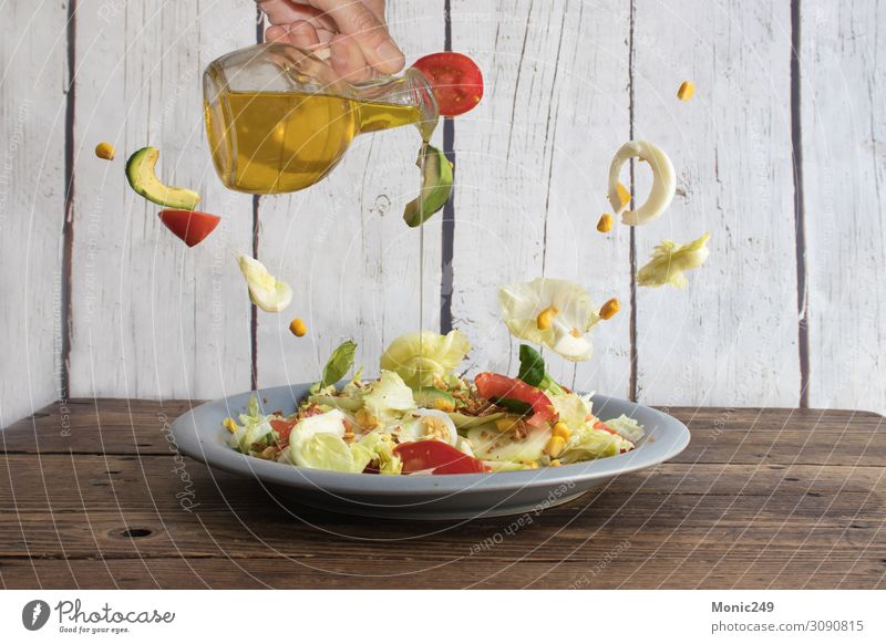 Menschliche Hand, die Olivenöl in den Salat gießt. Lebensmittel Gemüse Mittagessen Abendessen Vegetarische Ernährung Diät Teller Gabel Lifestyle Glück