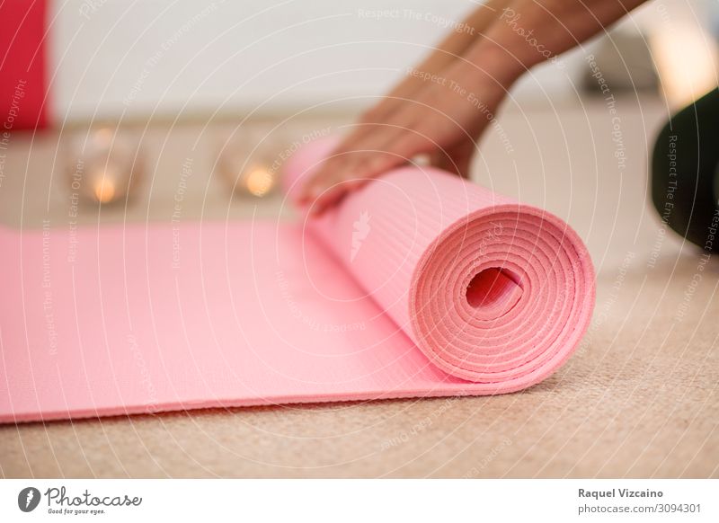 Frauenhände wickeln die rosa Yogamatte auf. Lifestyle Wellness Erholung Meditation Sport Hand Kerze atmen Gesundheit braun friedlich ruhig Zufriedenheit