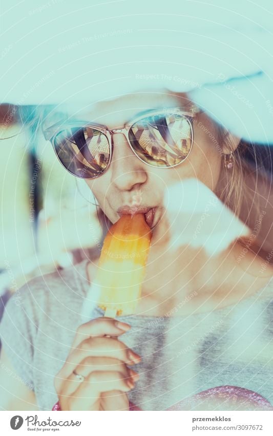 Junge Frau, die ein Eis isst und im Sommer auf einem Stuhl im Freien auf einer Terrasse sitzt Speiseeis Essen Lifestyle Erholung Ferien & Urlaub & Reisen Mensch