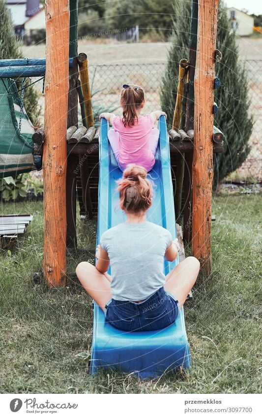 Schwestern beim gemeinsamen Spaß auf einer Rutsche Lifestyle Freude Sommer Sommerurlaub Garten Kind Familie & Verwandtschaft 2 Mensch 3-8 Jahre Kindheit