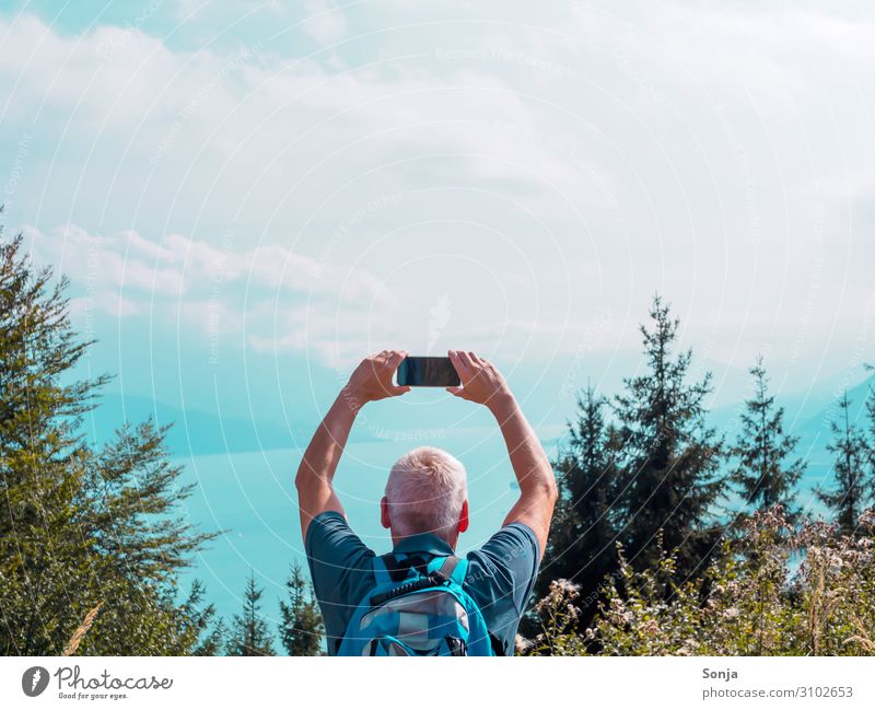 Mann über 40 auf einem Berg mit Handy und Blick auf einen See Lifestyle Freiheit wandern maskulin Erwachsene Leben 1 Mensch 45-60 Jahre Natur Wasser Himmel