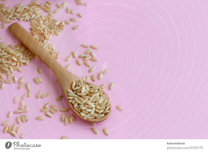 Brauner Reis in einem Holzlöffel Ernährung Vegetarische Ernährung Diät Löffel Tisch rosa Vollkornreis integral hellrosa Korn rustikal Gesundheit Zutaten Kerne
