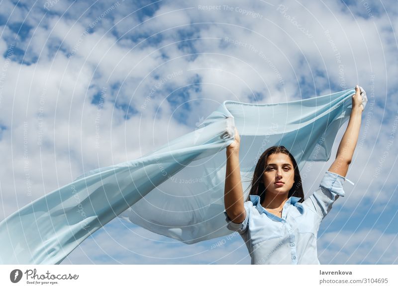 Junge Frau, die einen Schnitt aus blauem Stoff am Himmel hält. Erwachsene Air Einsamkeit attraktiv Wolken geschnitten Freiheit Hand Glück Höhe Horizont Natur