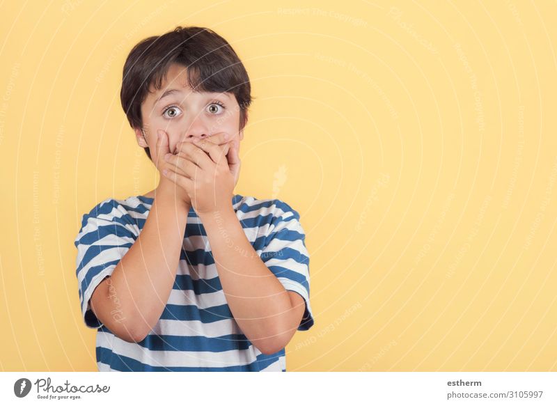 Kind bedeckt seinen Mund mit den Händen auf gelbem Hintergrund Mensch maskulin Arme Hand 1 8-13 Jahre Kindheit Bewegung festhalten Traurigkeit lustig Neugier