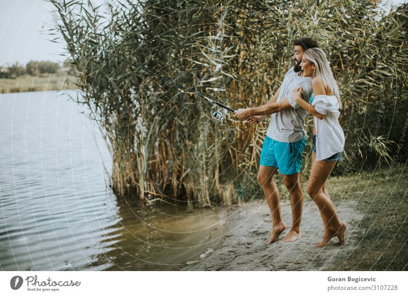 Junges Paar beim Angeln an einem sonnigen Tag an einem ruhigen See Lifestyle Glück schön Erholung Freizeit & Hobby Camping Sommer Sonne Entertainment Frau
