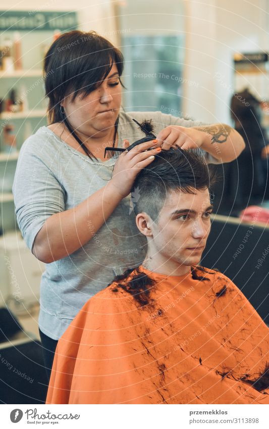 Der Friseur schneidet Haare, indem er junge Männer frisiert. Lifestyle kaufen Stil Haare & Frisuren Arbeit & Erwerbstätigkeit Beruf Schere Frau Erwachsene Mann