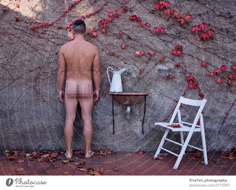 Erwachsener nackter Mann im herbstlichen Hinterhof mit weißem Krug und Stuhl mit zensiertem Rahmen. Totale Stil Fotografie Lifestyle schön Gesundheitswesen