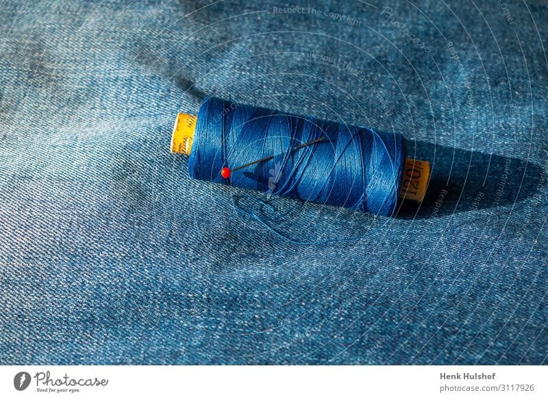 Garnrolle auf einer Blue Jeans Arbeitsplatz Mode Bekleidung Jeanshose Stoff Metall Kunststoff schön Reparatur Nadel blau Handjob Schnur Spule Farbfoto