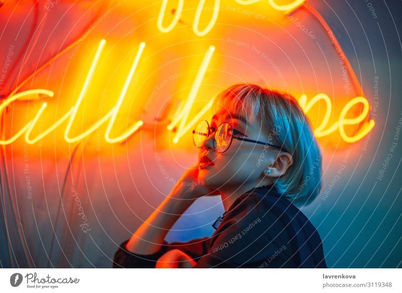 Asiatin mit Brille vor Neonlichtschild Asiate Frau Junge Frau Jugendliche 18-30 Jahre Licht Beleuchtung Illumination Nachtleben kurzhaarig blond rot orange
