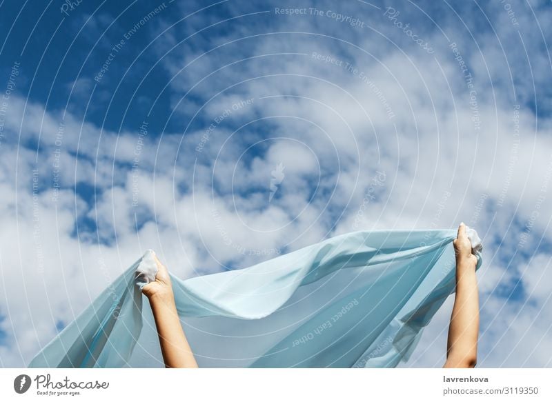 Weibliche Hände halten den Schnitt eines blauen Stoffes am Himmel fest. Horizont Höhe Etage fliegen Aussicht Luft Hand Außenaufnahme Sommer Natur Einsamkeit