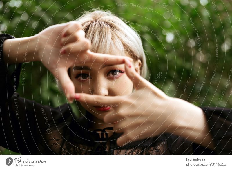 Nahaufnahme von jungen Erwachsenen blondes asiatisches Mädchen macht Rahmen Geste Auge Park Photo-Shooting Hand Lifestyle Gesicht Asiate 18-30 Jahre Junge Frau