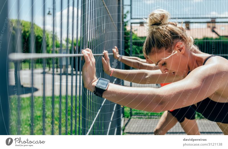 Zwei junge Sportlerinnen ruhen sich auf dem Zaun aus rollen Lifestyle schön Körperpflege Mensch Frau Erwachsene Freundschaft brünett blond Fitness sportlich
