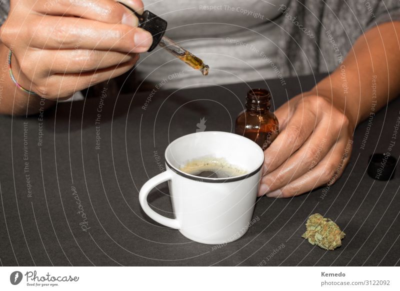Frau, die Cannabisöl (hergestellt mit Marihuana) in eine Kaffeetasse gießt. Dessert Kräuter & Gewürze Frühstück Getränk Tasse Becher Lifestyle Freude Gesundheit