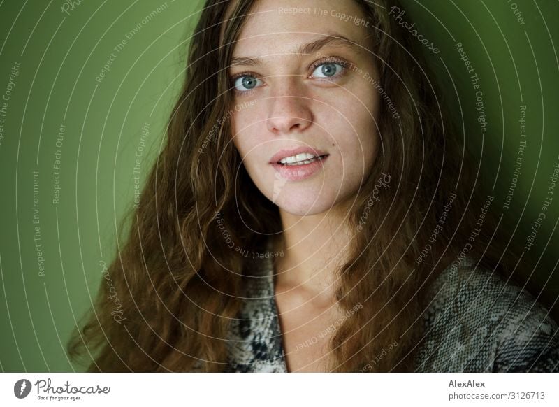 Portrait einer jungen Frau vor grüner Wand Stil Freude schön Wellness Leben Junge Frau Jugendliche 18-30 Jahre Erwachsene brünett langhaarig beobachten Blick