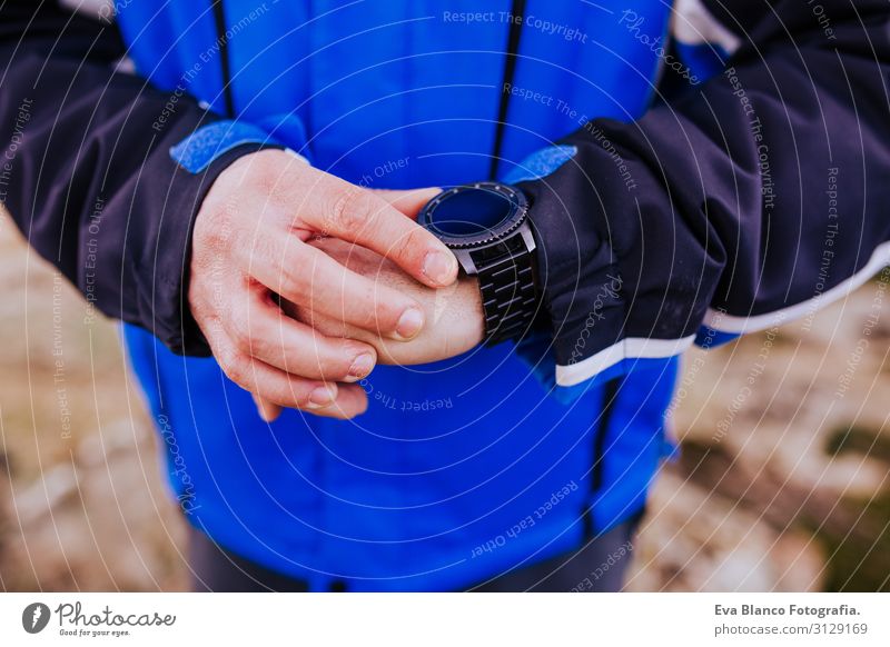 junger Wanderer, der auf dem Gipfel des Berges eine schlaue Uhr kontrolliert. bewölkter Tag Bildschirm intelligente Uhr wandern App ultra Läufer Training