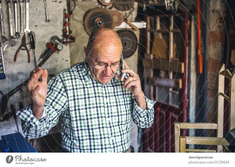 Schreiner in seiner Werkstatt Stuhl Handwerk Business sprechen Mensch Mann Erwachsene Holz alt authentisch Senior Zimmerer argumentierend Funktelefon Mobile
