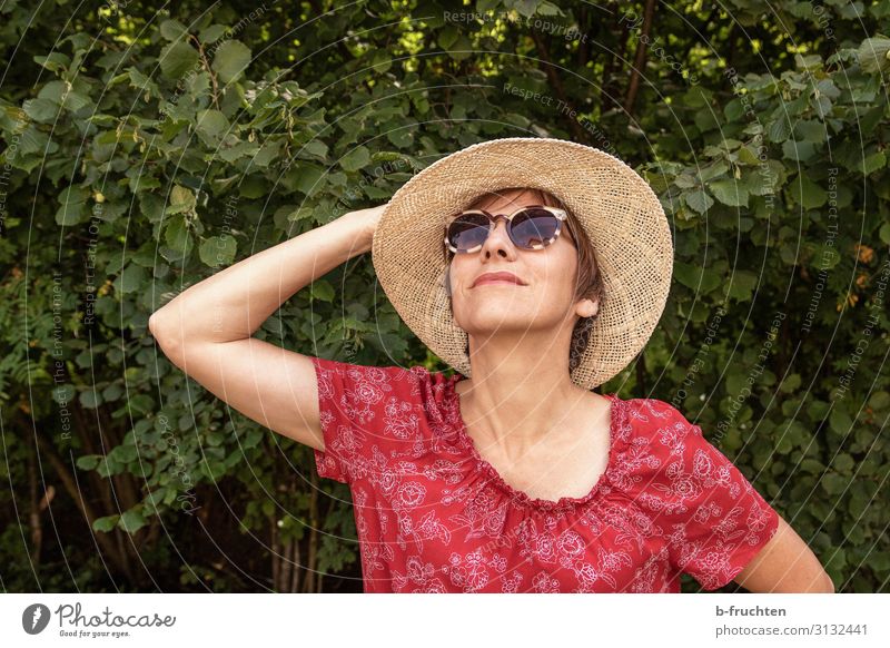 Frau mit Sonnenhut Lifestyle Stil Wohlgefühl Freizeit & Hobby Erwachsene Gesicht Hand 1 Mensch Sommer Sträucher Kleid Sonnenbrille Hut Erholung festhalten
