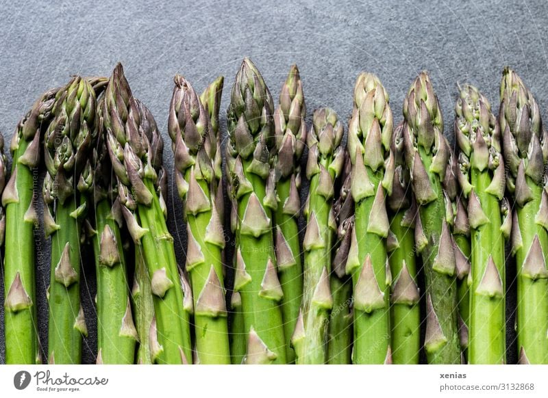 grüner Spargel auf grauer Arbeitsplatte Lebensmittel Spargelstangen Gemüse Ernährung Bioprodukte Vegetarische Ernährung Diät Frühling frisch Gesundheit lang