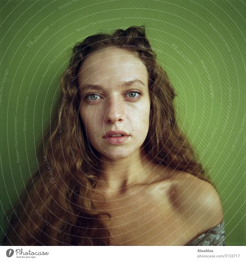 Rechteckiges Portrait einer jungen Frau vor grüner Wand Stil schön Leben Junge Frau Jugendliche Haare & Frisuren Gesicht Model 18-30 Jahre Erwachsene brünett