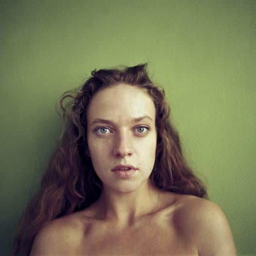 Rechteckiges Portrait einer jungen Frau vor grüner Wand elegant schön Leben Junge Frau Jugendliche Gesicht Schulter 18-30 Jahre Erwachsene brünett langhaarig