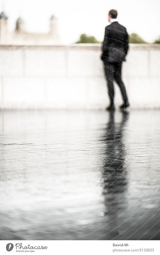 Mann mit Anzug steht im Regen Anzugträger Regenwetter Business schlechtes Wetter Schatten Spiegelung Schattenseite Schattendasein Schattenwurf