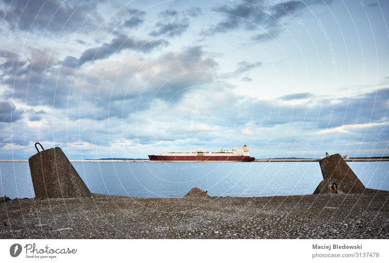Betonmolenmauer mit einem Schiff in der Ferne bei Sonnenuntergang. Meer Himmel Hafen Verkehr Schifffahrt Öltanker Wasserfahrzeug maritim Schutz Zufriedenheit