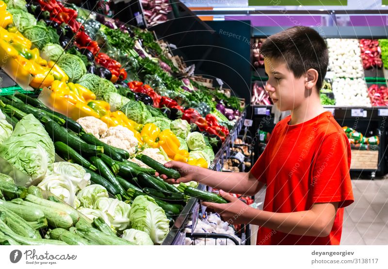 Kind wählt Gemüse im Regal im Supermarkt aus. Lebensmittel Vegetarische Ernährung kaufen Marktplatz stehen frisch natürlich Käufer auswählend Teenager