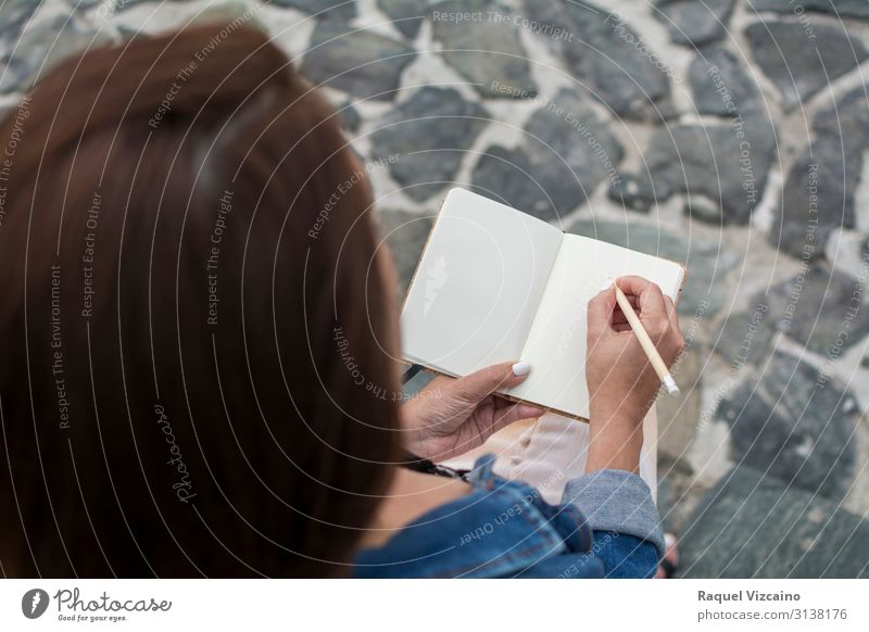 Eine Frau hält ein leeres Notizbuch. Lifestyle lesen Bildung Erwachsenenbildung Mensch 18-30 Jahre Jugendliche Buch schreiben sitzen Beginn Notebook blanko