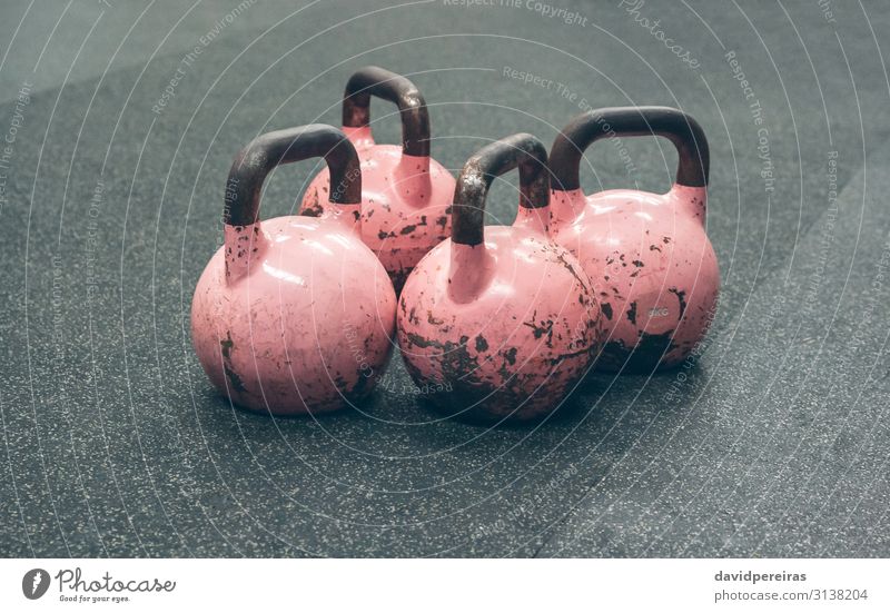 Kettlebells auf dem Boden eines Fitnessstudios Sport rosa Sporthalle Kasten Gewichte vier gebraucht durchkreuzen passen vereinzelt Wasserglocke verschlissen