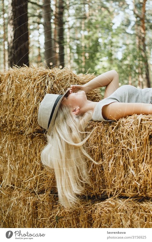 Blonde Frau mit Hut liegend Heustadel, selektiver Fokus Junge Frau Glück festlich Park Wald attraktiv Dorf Landschaft deckend blond Kaukasier Natur Sommer