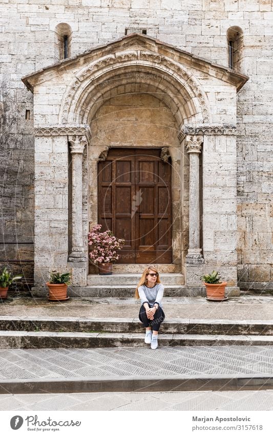 Junge Frau, die auf den Stufen einer alten Kirche sitzt. Lifestyle Ferien & Urlaub & Reisen Tourismus Ausflug Sightseeing feminin Jugendliche Erwachsene 1
