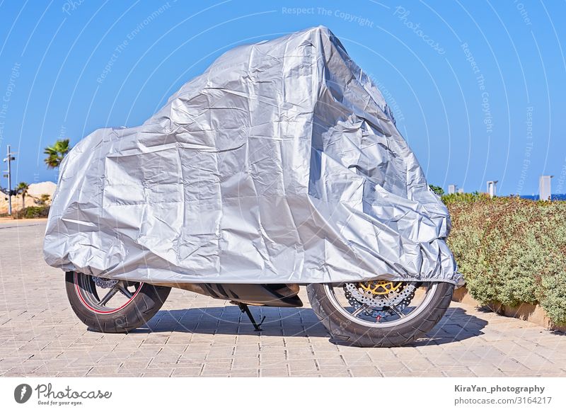 Wasserdichte Abdeckung für Motorrad mit silber reflektierender Schutzoberfläche. Motorrad mit Stoffschild überzogen und im Freien geparkt Deckung blau