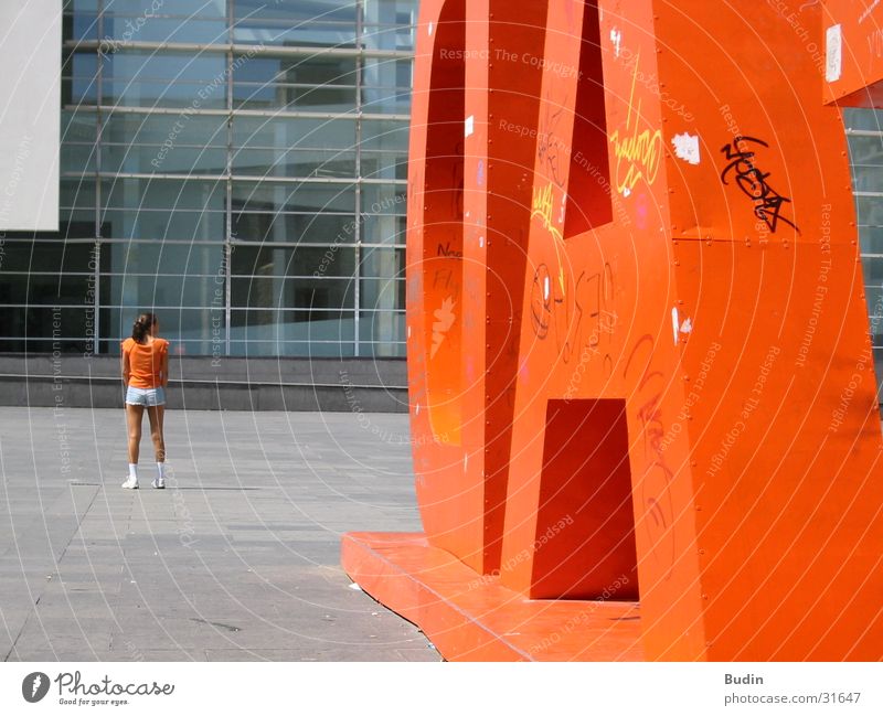 Orange Frau Mädchen Buchstaben Blech Barcelona orange Rücken rückwärts Glasfassade Kontrast