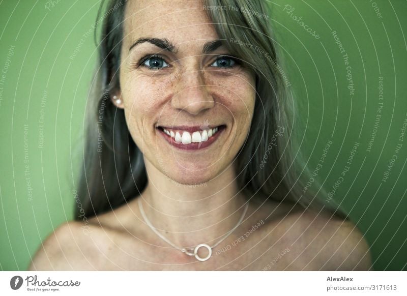 Portrait einer lächelnden Frau mit Sommersprossen vor grüner Wand Stil Freude schön Leben harmonisch Erwachsene 30-45 Jahre Schmuck blond langhaarig Lächeln