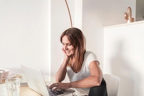 Glückliche erwachsene Frau, die zu Hause mit dem Laptop arbeitet Lifestyle kaufen schön lesen Lampe Schreibtisch Tisch Wohnzimmer Erfolg