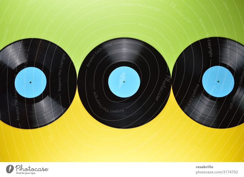 drei alte schwarze Vinyl Schallplatten auf buntem grünem und gelbem Hintergrund | Dreiklang LP antik vintage Musik Disco Langspielplatte abspielen neutral