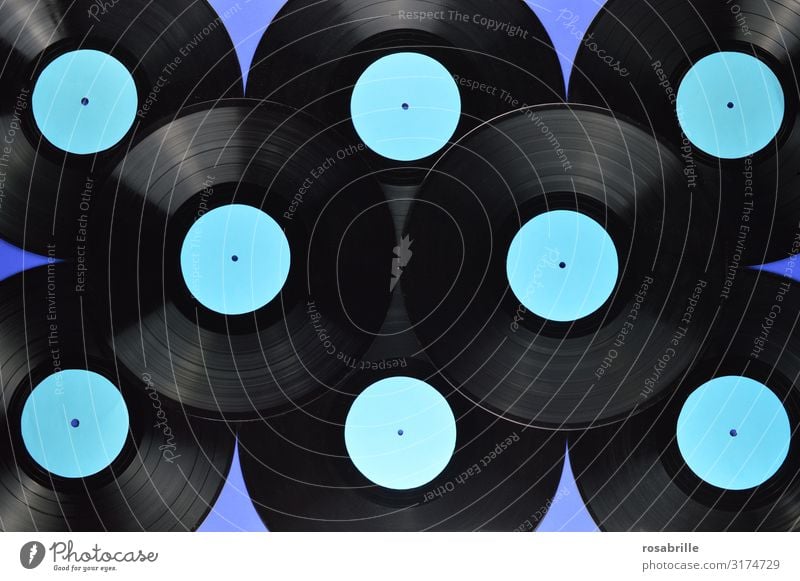 viele alte schwarze Vinyl Schallplatten aufeinander gestapelt mit leerem türkis farbenem Label auf blauem Hintergrund | Symmetrie LP antik retro vintage Musik