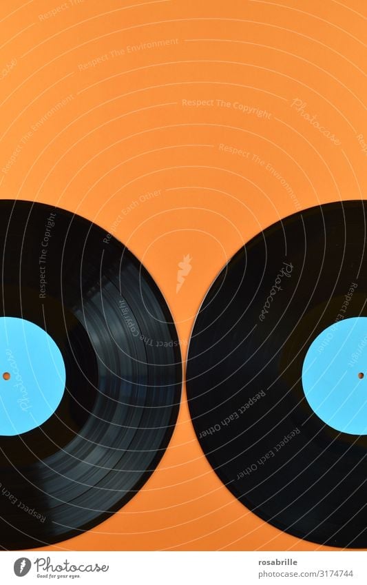 zwei alte schwarze Vinyl Schallplatten zur Hälfte im Bild mit leerem türkis farbenem Label auf orangenem Hintergrund mit Freiraum für Text oben| Symmetrie LP