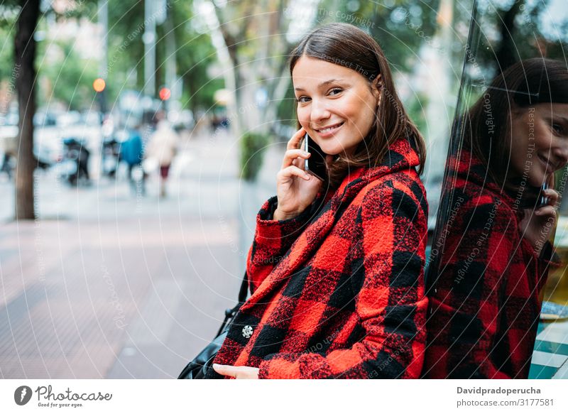 hübsche junge Frau steht auf Glas auf der Straße mit Smartphone Zelle benutzend Technik & Technologie Lächeln Tageslicht Wegsehen Gerät Apparatur Gespräch