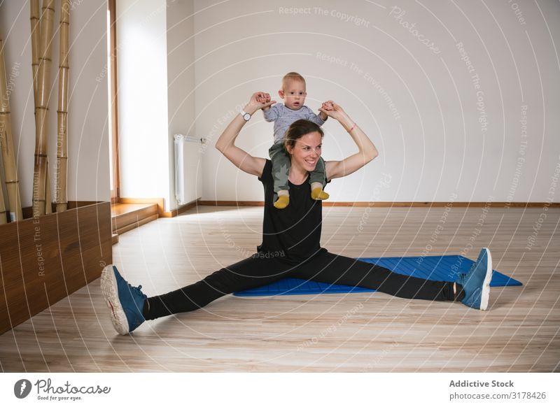 Mutter beim Training mit dem Baby im Fitnessstudio Sporthalle üben Etage Bauchmuskeln modern Lifestyle Frau Kind Glück Lächeln heiter Freude Sportbekleidung