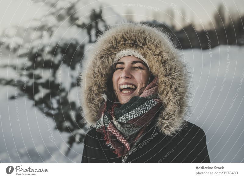 Junge Frau lacht auf verschneitem Hintergrund lachen Freude Schnee attraktiv Jugendliche Wärme Bekleidung Pelzmantel Baum Konifere Winter Glück Fröhlichkeit