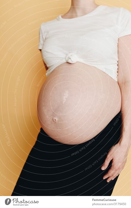 Schwangere Frau zeigt ihren Babybauch - neutraler Hintergrund feminin Erwachsene 1 Mensch 18-30 Jahre Jugendliche 30-45 Jahre Glück schwanger Nachkommen