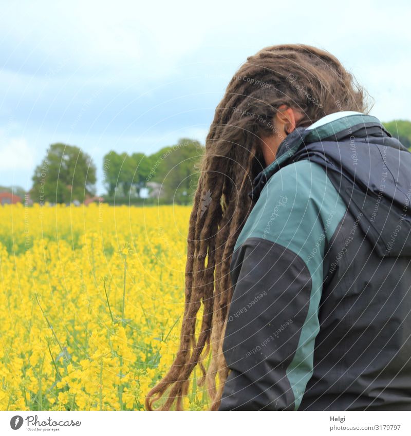Frau mit langen Dreadlocks vor dem Gesicht steht an einem gelb blühenden Rapsfeld Mensch feminin Erwachsene 1 30-45 Jahre Umwelt Natur Landschaft Pflanze