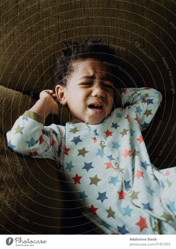 Schwarzes Kind bereit zum Weinen Junge weinen Sofa heimwärts Pyjama Traurigkeit Raum klein schwarz Afroamerikaner urwüchsig Problematik Kleinkind niedlich