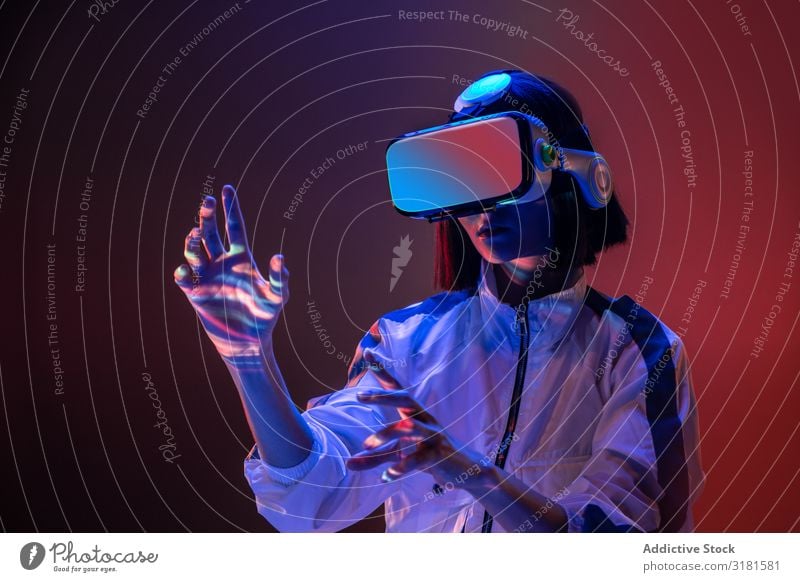 Frau berührt Luft in VR-Brillen asiatisch Headset Virtuelle Realität Technik & Technologie neonfarbig Licht berühren Gerät digital Innovation Brillenträger
